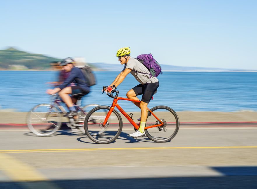 Deux cyclistes roulant sur une route littorale face à l'océan