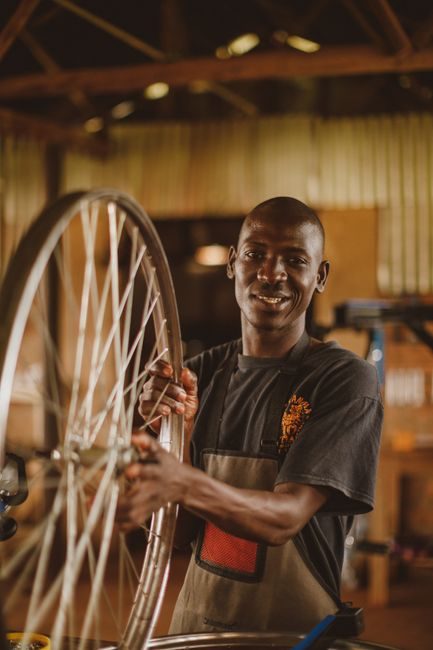 Le gérant de VELOLOGUE dans son atelier, une roue de vélo entre les mains