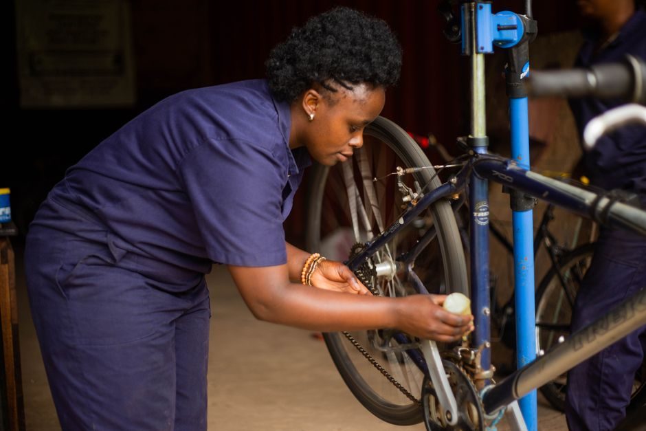 Mécanicienne réglant la transmission d'un vélo à l'établi