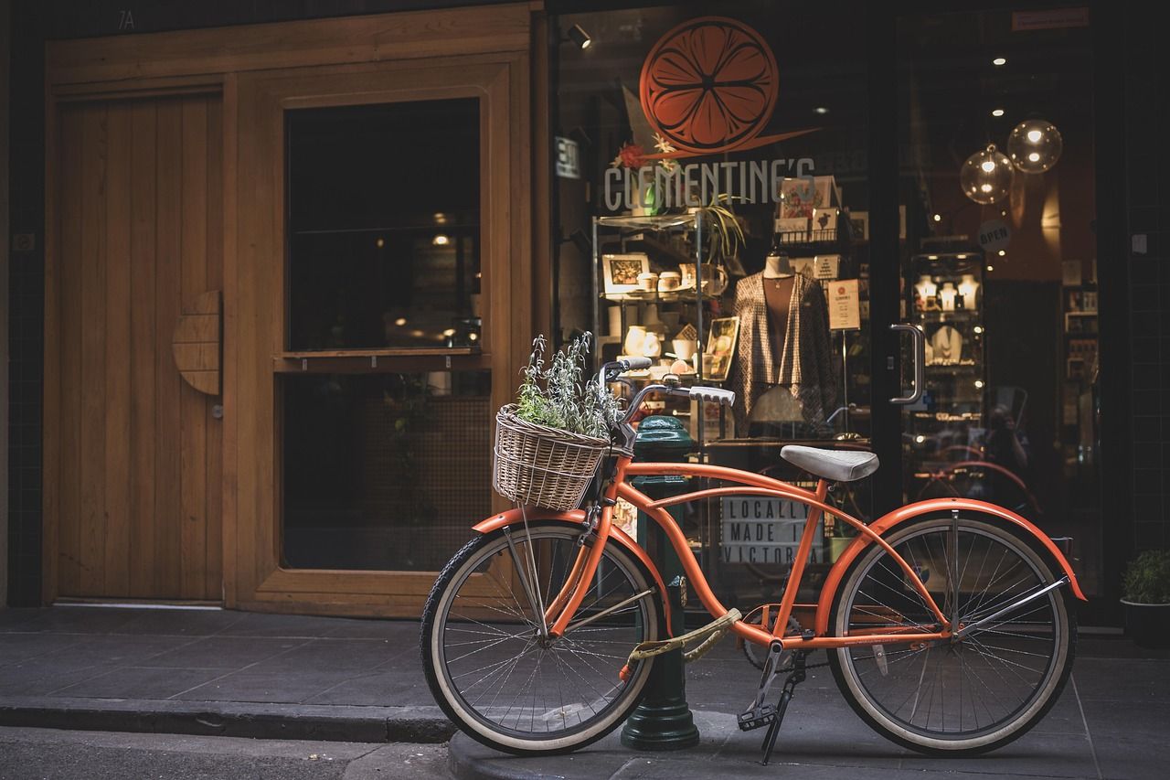 Vélo de ville orange complet, équipé et prêt à l'usage devant une boutique